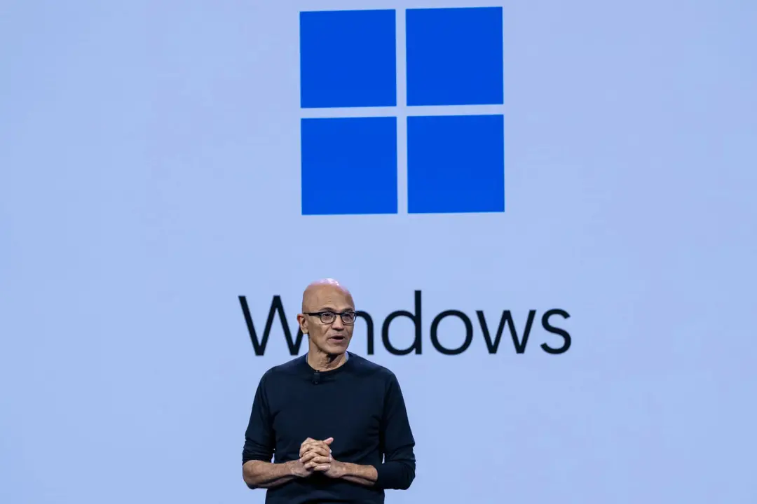 ساتی نادلا (Satya Nadella) در مقابل لوگوی ویندوز (Windows) ایستاده است