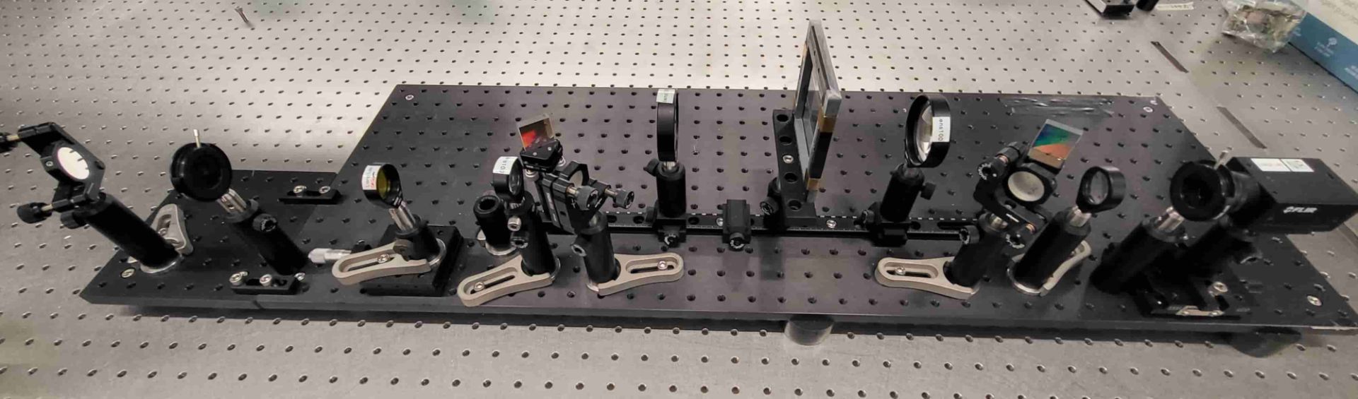 یک بورد سیاه که روی آن چندین عدسی و آینه قرار دارد 