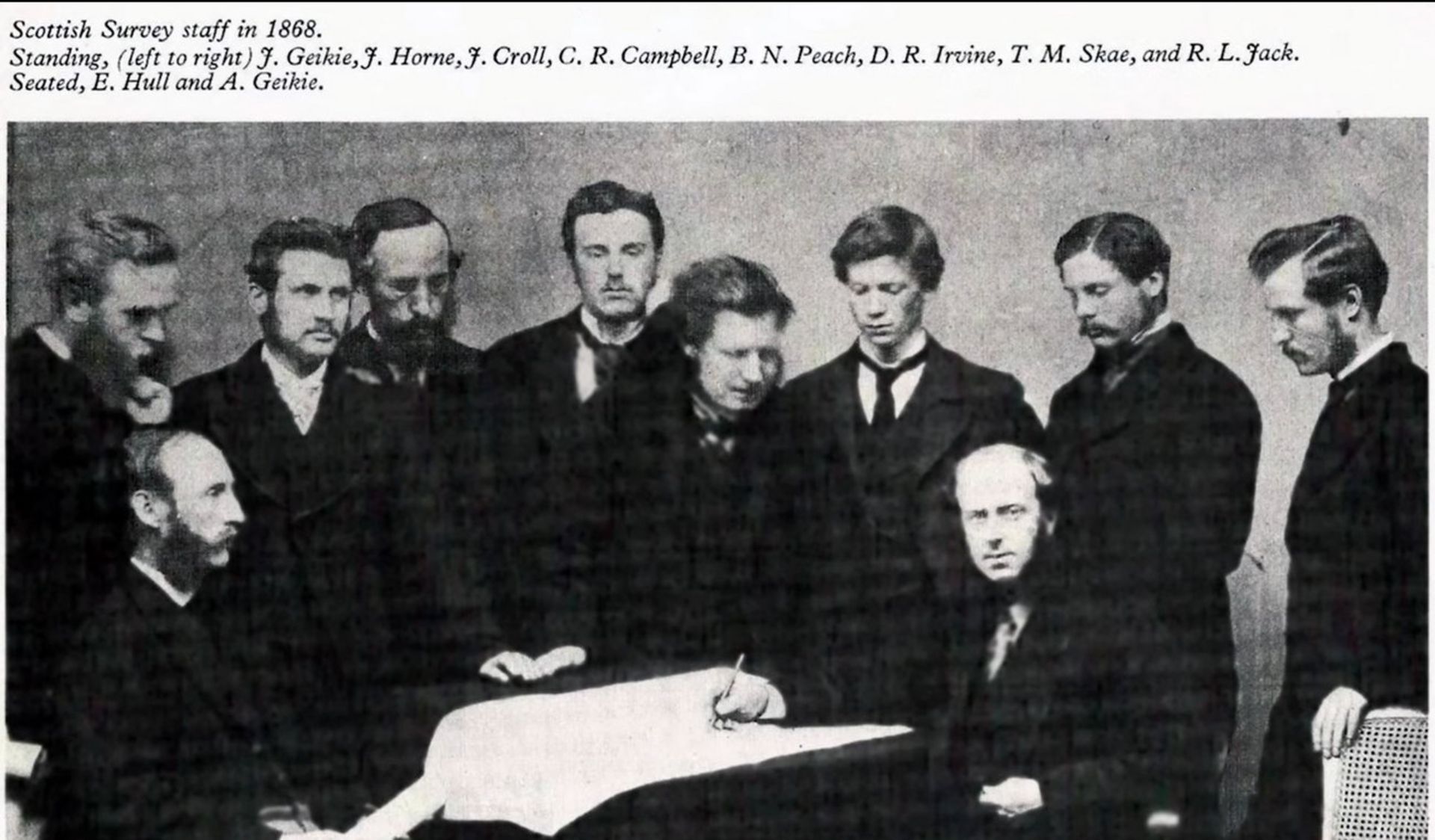 گروه تحقیقاتی اسکاتلند در سال ۱۹۸۶ عکس قدیمی و سیاه و سفید چند مرد ایستاده و نشسته با لباس رسمی