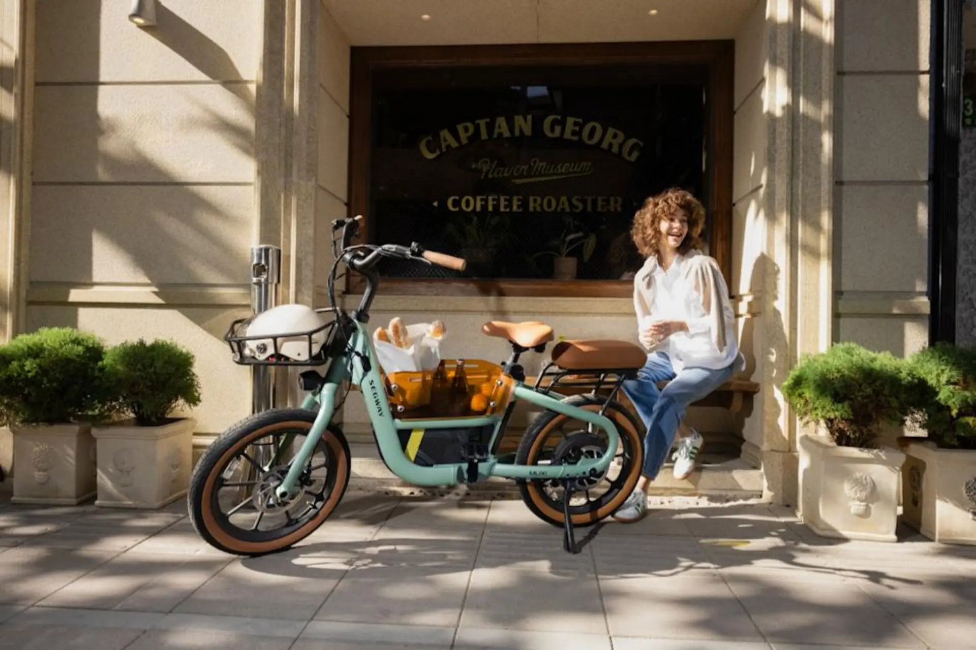 زن جوان کنار دوچرخه‌‌ی برقی سگوی