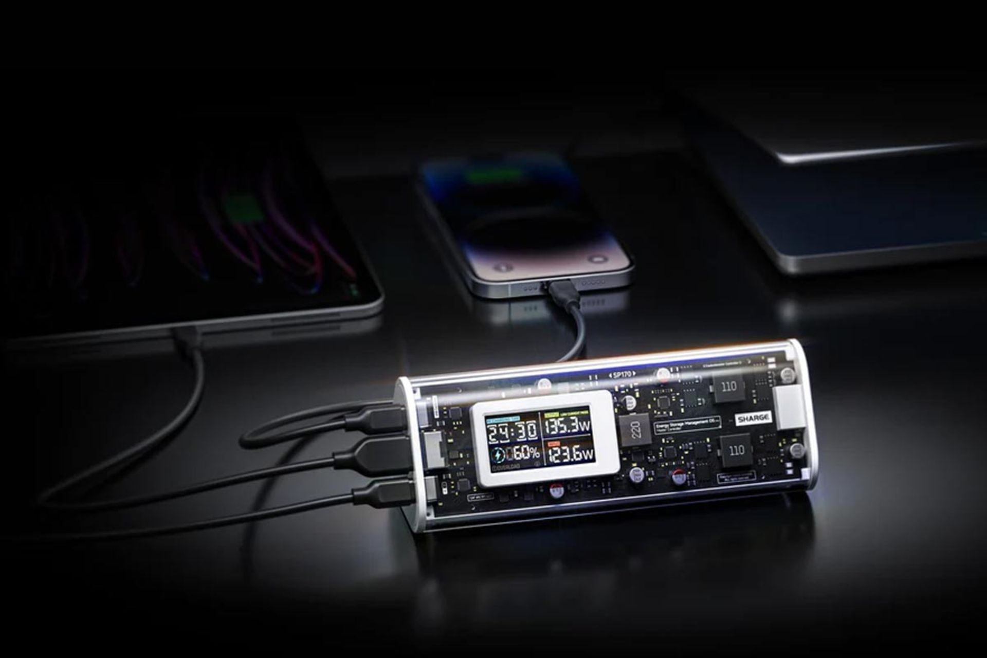 پاوربانک شارگیک ۱۷۰ در حال شارژ سه دستگاه تبلت، گوشی و لپ تاب همزمان در پس‌زمینه مشکی و تاریک