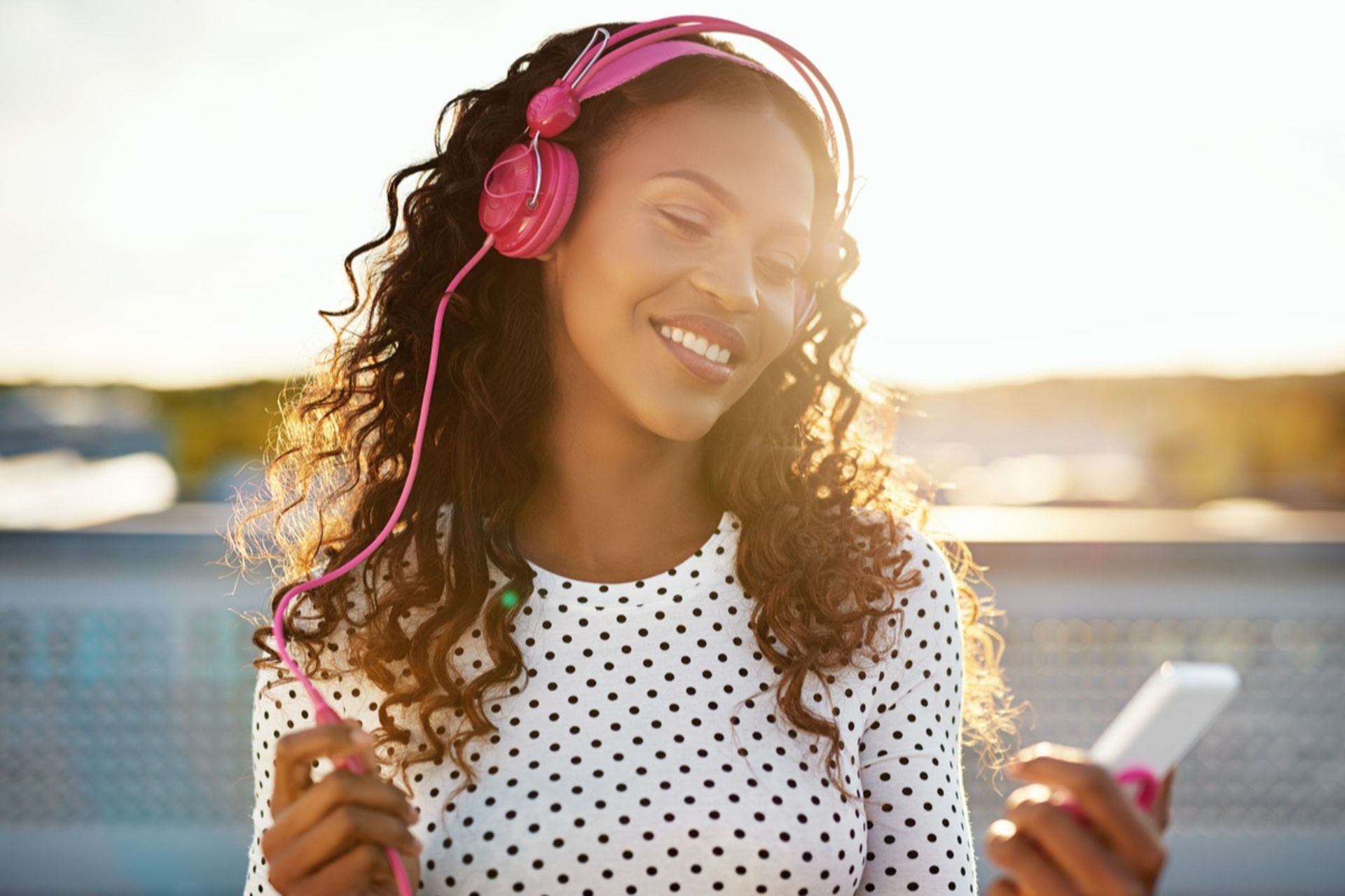 زن جوان درحال گوش‌کردن به موسیقی با هدفون است