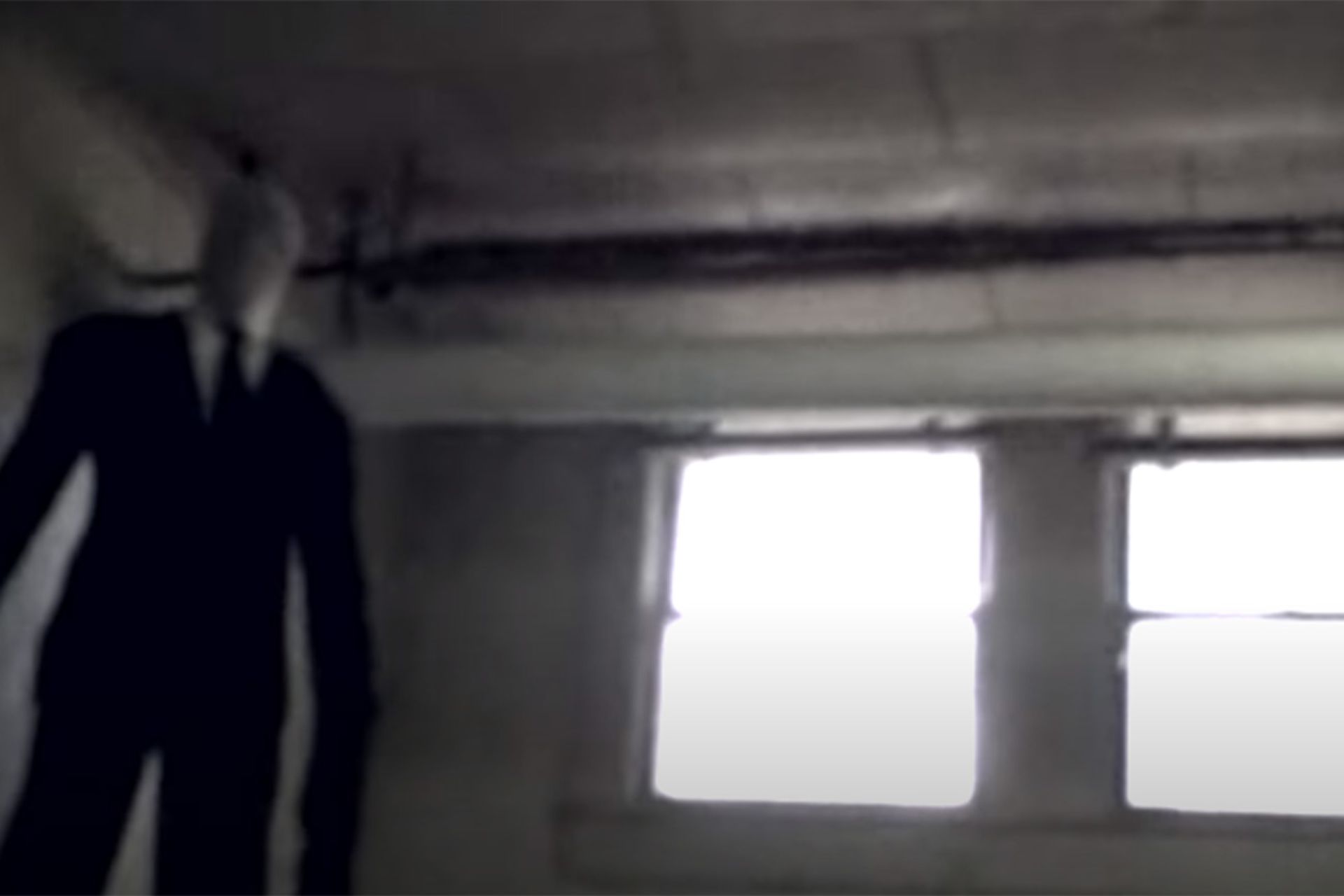 مرد بلندقامتی با کت‌وشلوار مشکی و دستانی بسیار بلند در اتاق