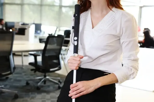 عصای سفید هوشمند (Smart White Cane) در دست یک زن در محیط اداری