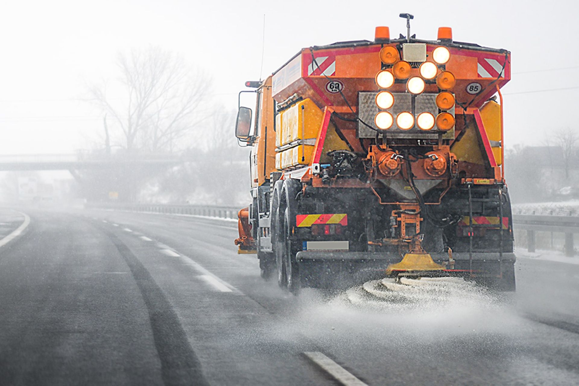 کامیون در حال نمک پاشیدن در جاده‌ی یخ‌زده