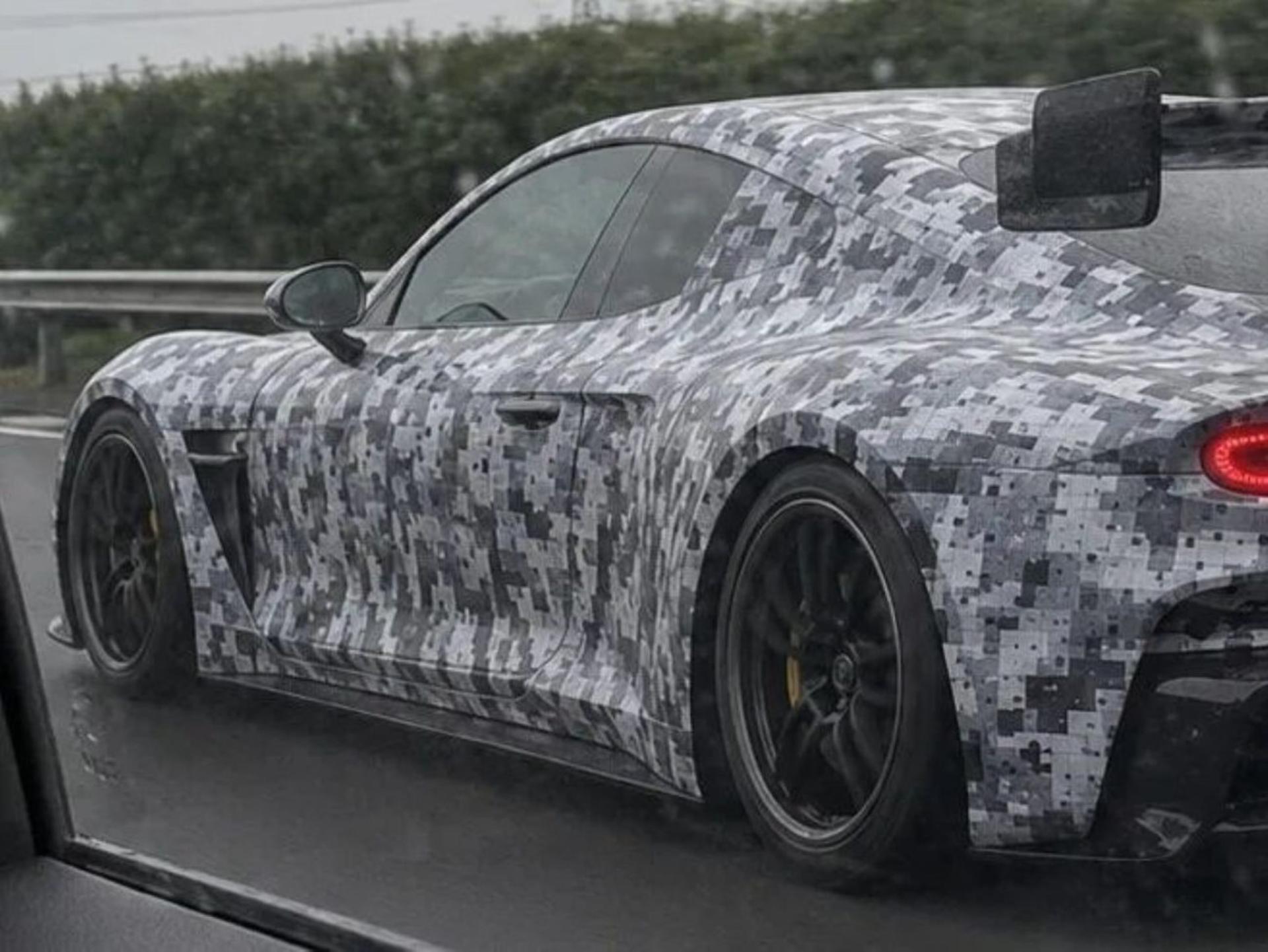 یک خودروی اسپرت با بدنه پوشیده شده با طرح استتار دیجیتال خاکستری و سیاه در حال حرکت