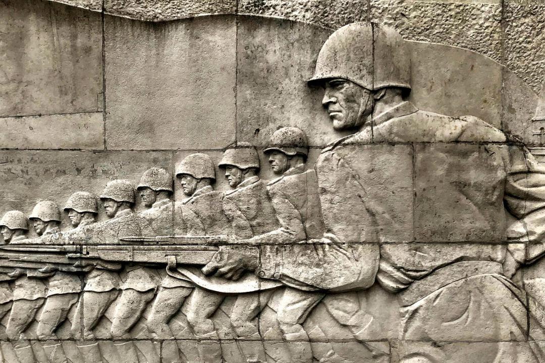 نقش برج سنگی از گروهی سرباز مسلح که در یک صف منظم در حال حرکت هستند.