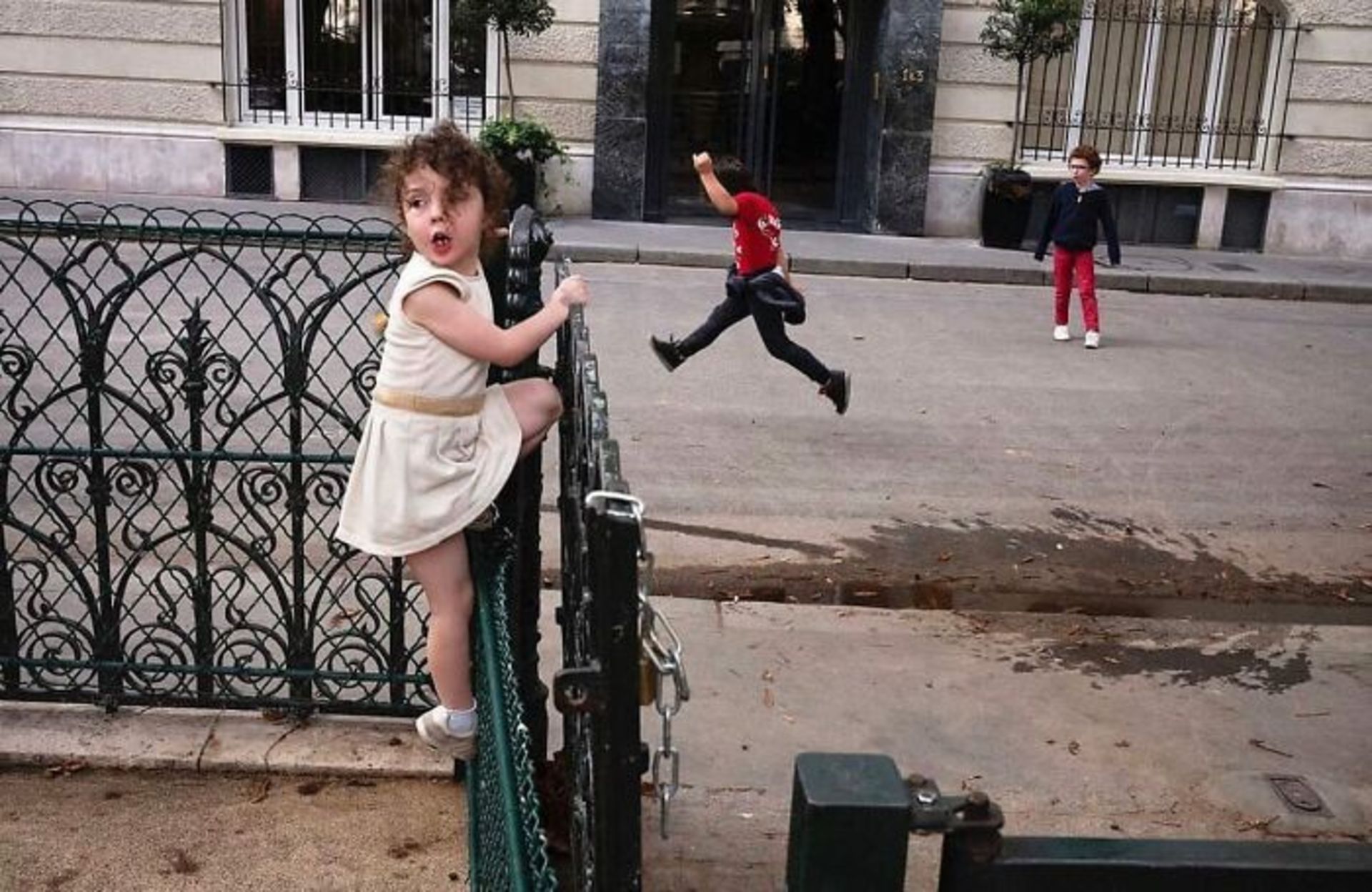 دختربچه در حال بالا رفتن از حصار خانه و پیوستن به پسران در حال بازی