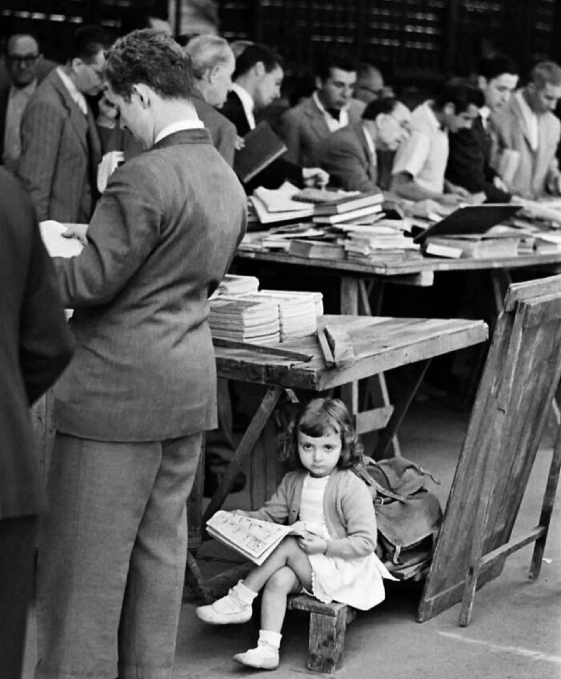 دختربچه در حال مطالعه در جمعه از مردان و کتاب های روی میز