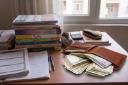 کتاب‌های درسی کنکور و کیف پول پر از اسکناس روی میز مطالعه