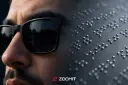 مردی با عینک آفتابی در کنار نوشته‌های خط بریل (Braille)