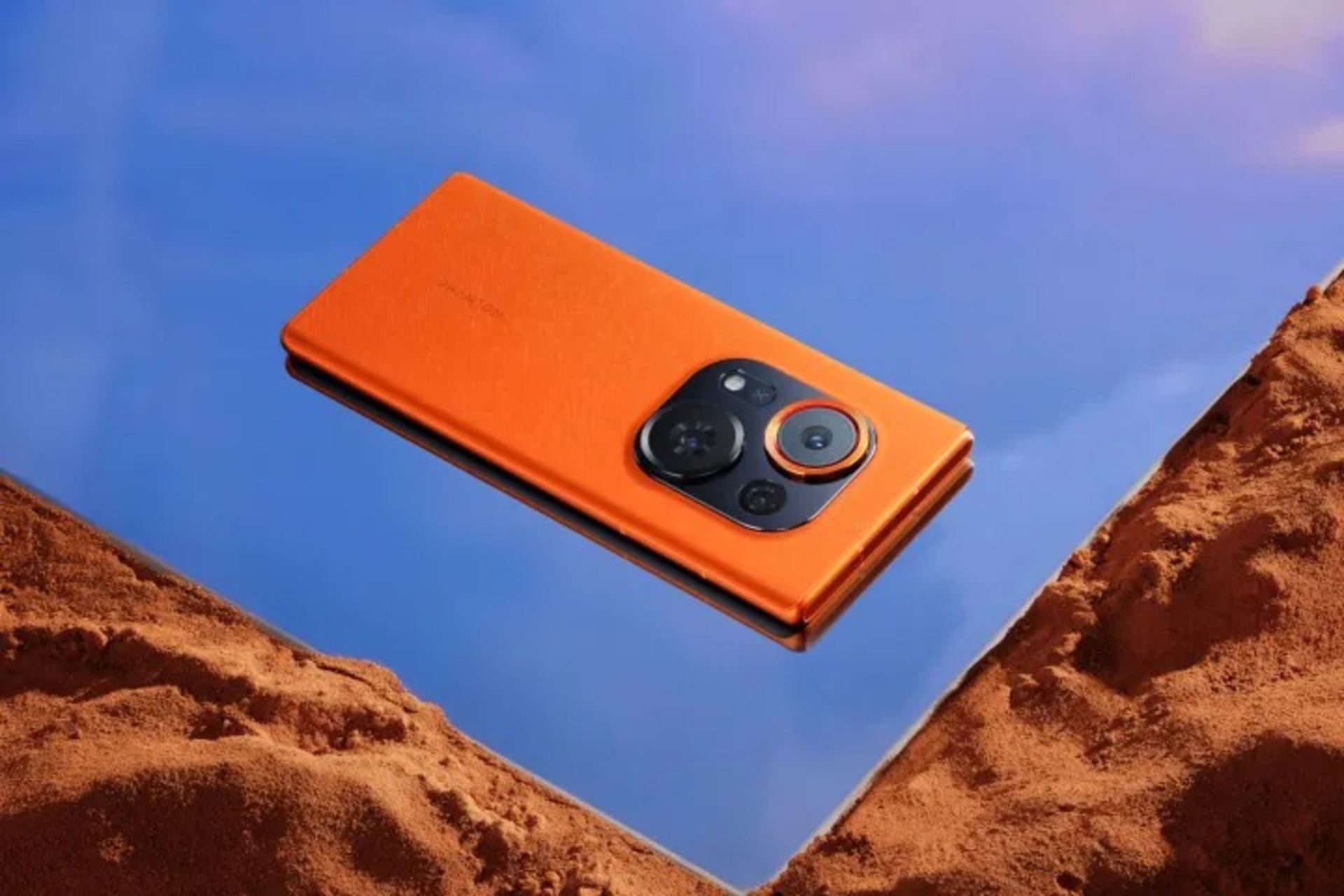 قاب پشتی گوشی تکنو رنگ نارنجی قرار گرفته روی شن