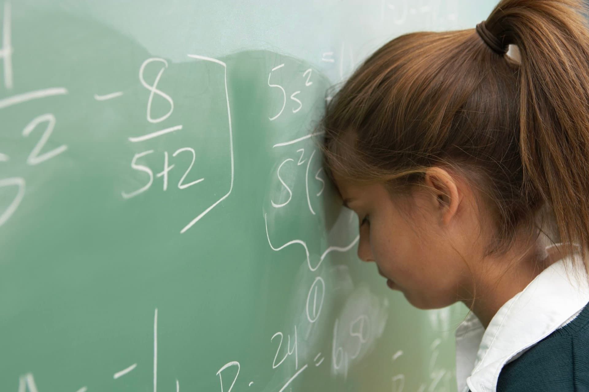 دختر دانش آموز مشغول حل مسئله ریاضی روی تخته سیاه