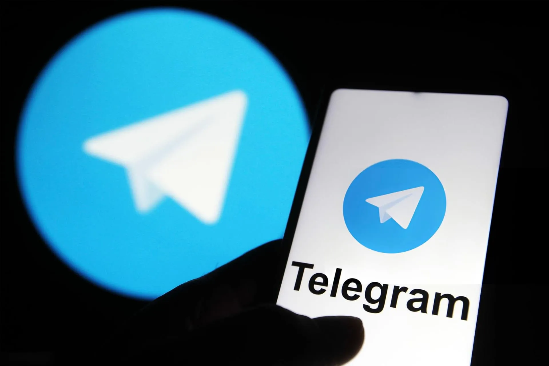 Telegram logo inside the phone and black and blue background