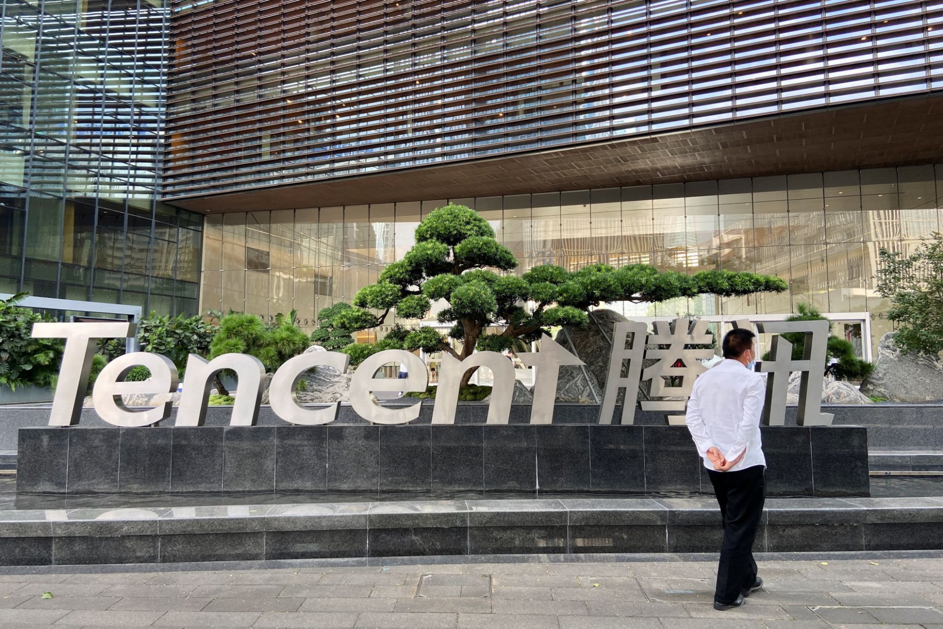 مردی درحال عبور از کنار لوگو Tencent جلو یک ساختمان