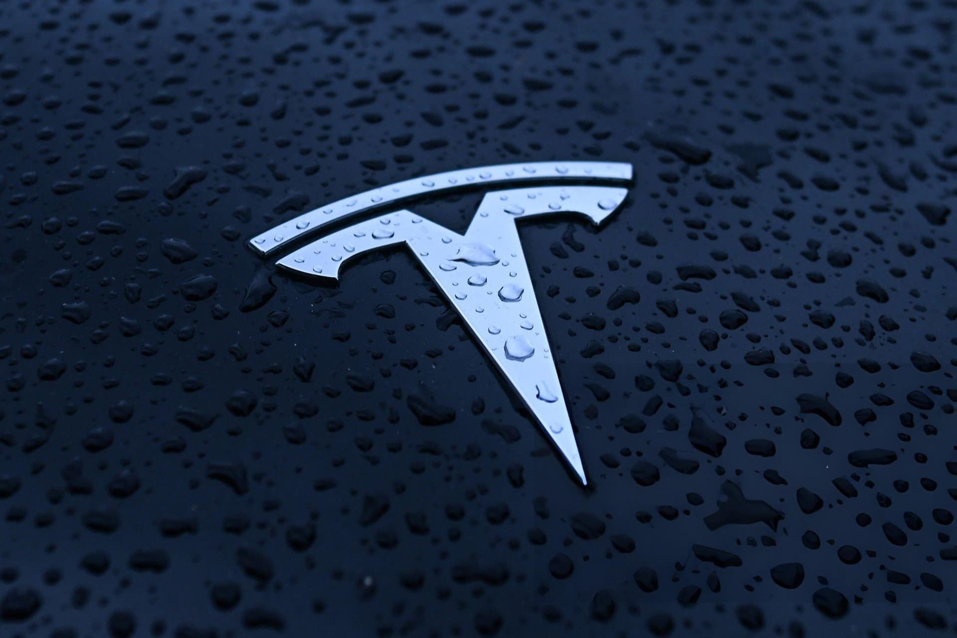 نمای نزدیک لوگو تسلا / Tesla در زیر باران رنگ مشکی و نقره‌ای