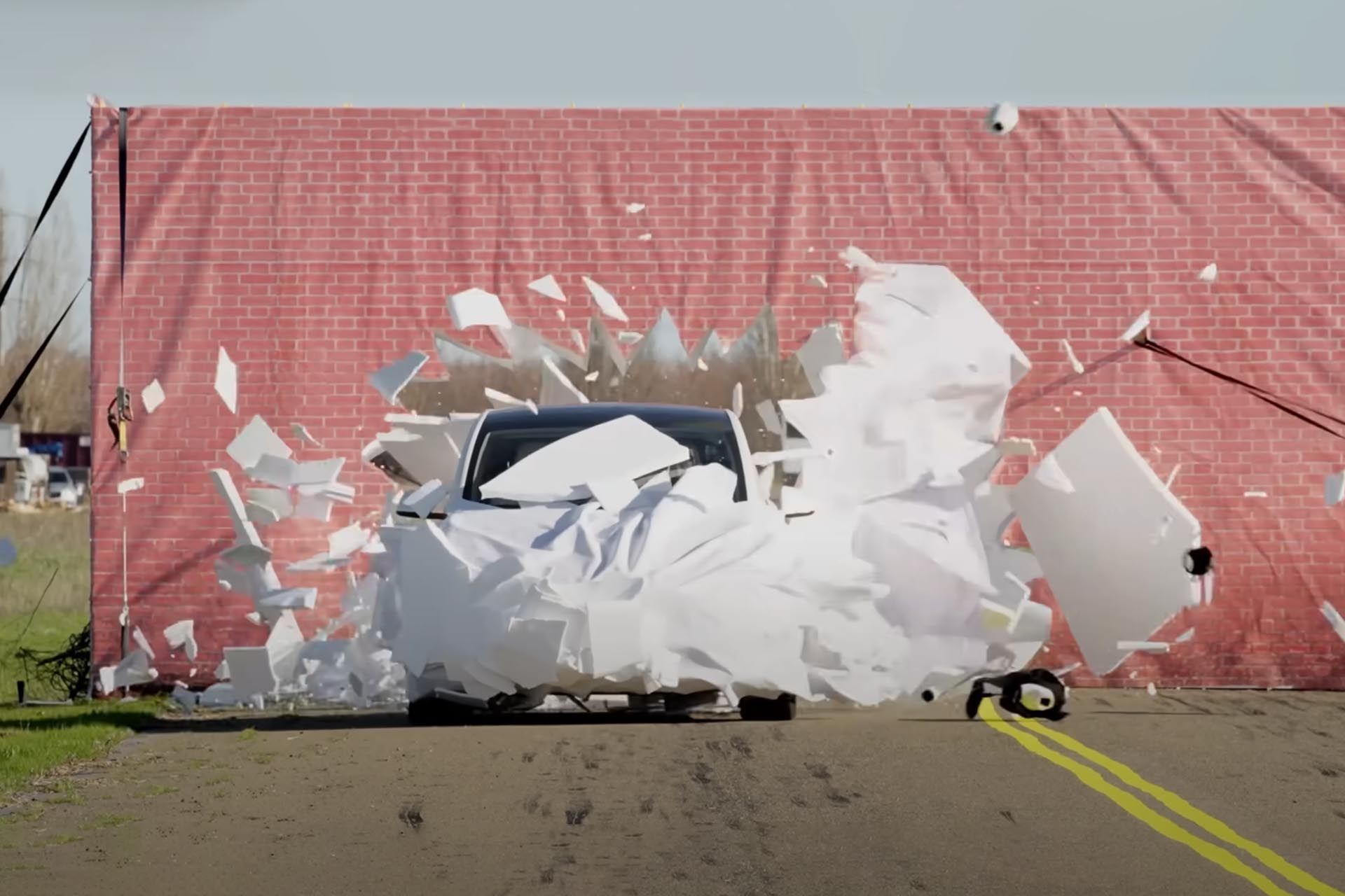 خودروی تسلا از نمای جلو درحال عبور از دیوار نقاشی شده