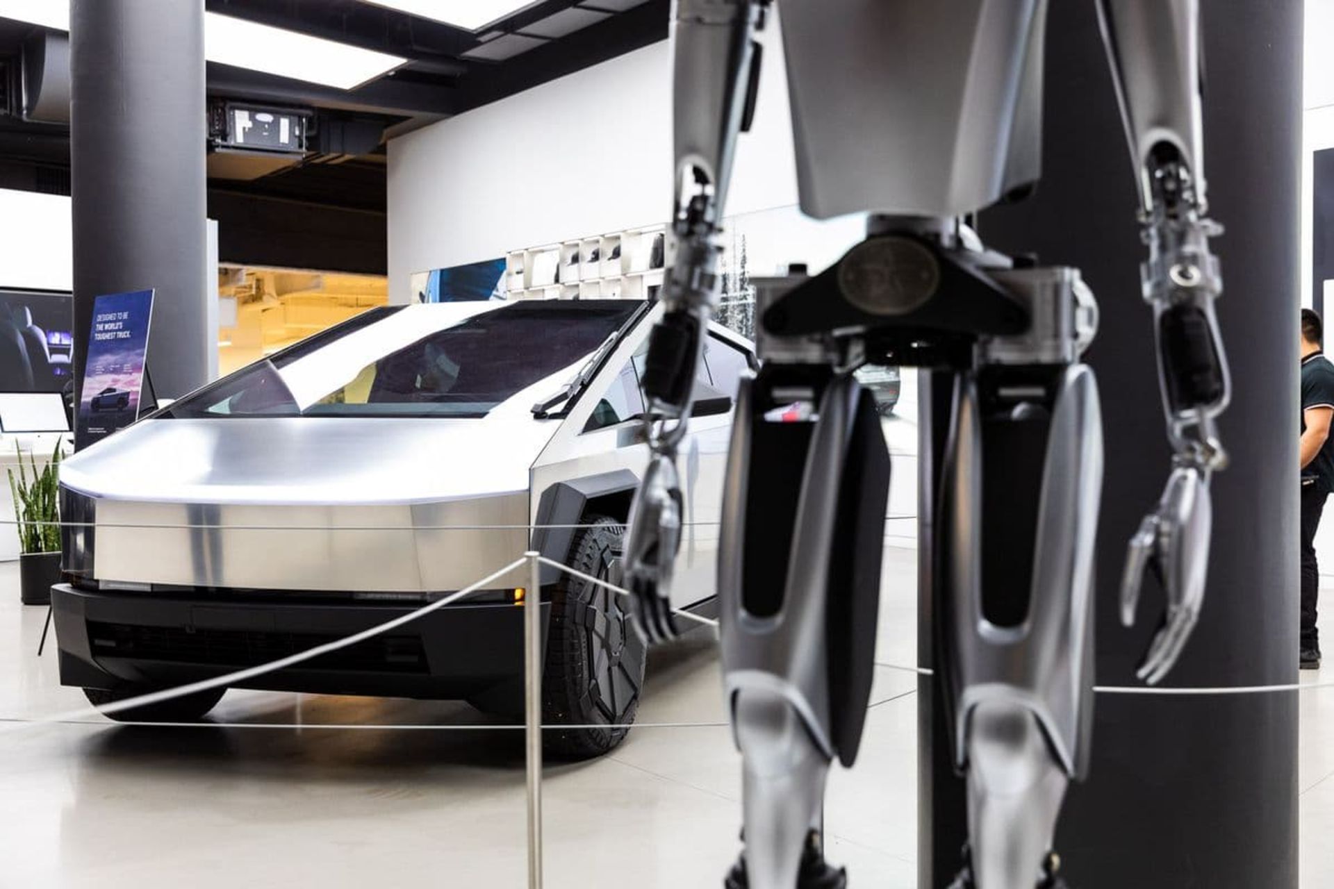 نمای کناری خودرو سایبرتراک تسلا در مقابل یک ربات تزئینی در نمایشگاه منهتن