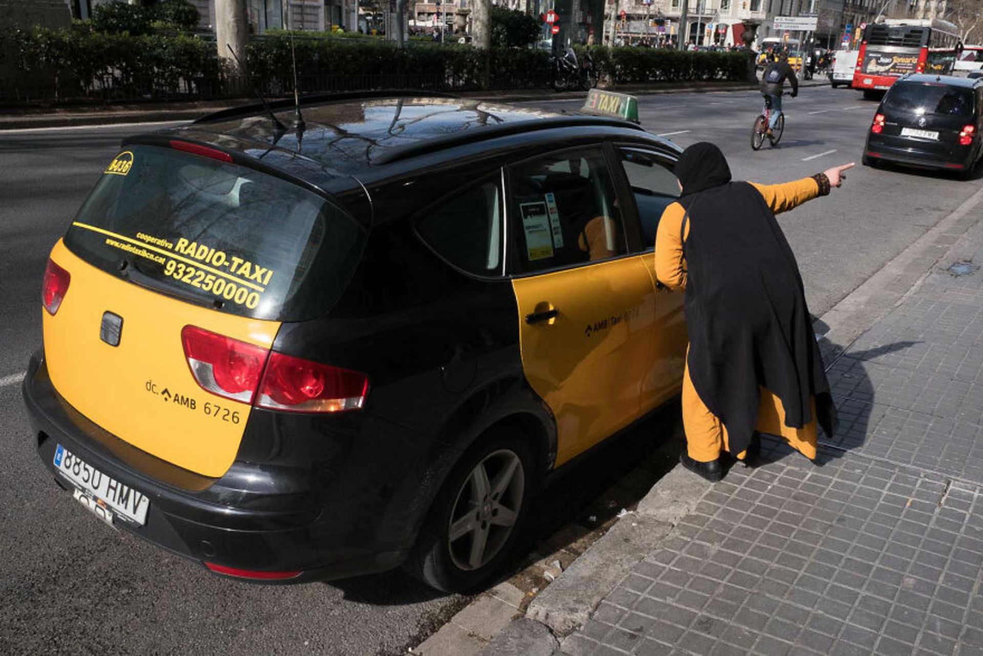 زن با لباس مشکی و زرددر حال آدرس دادن به ماشینی زرد سیاه