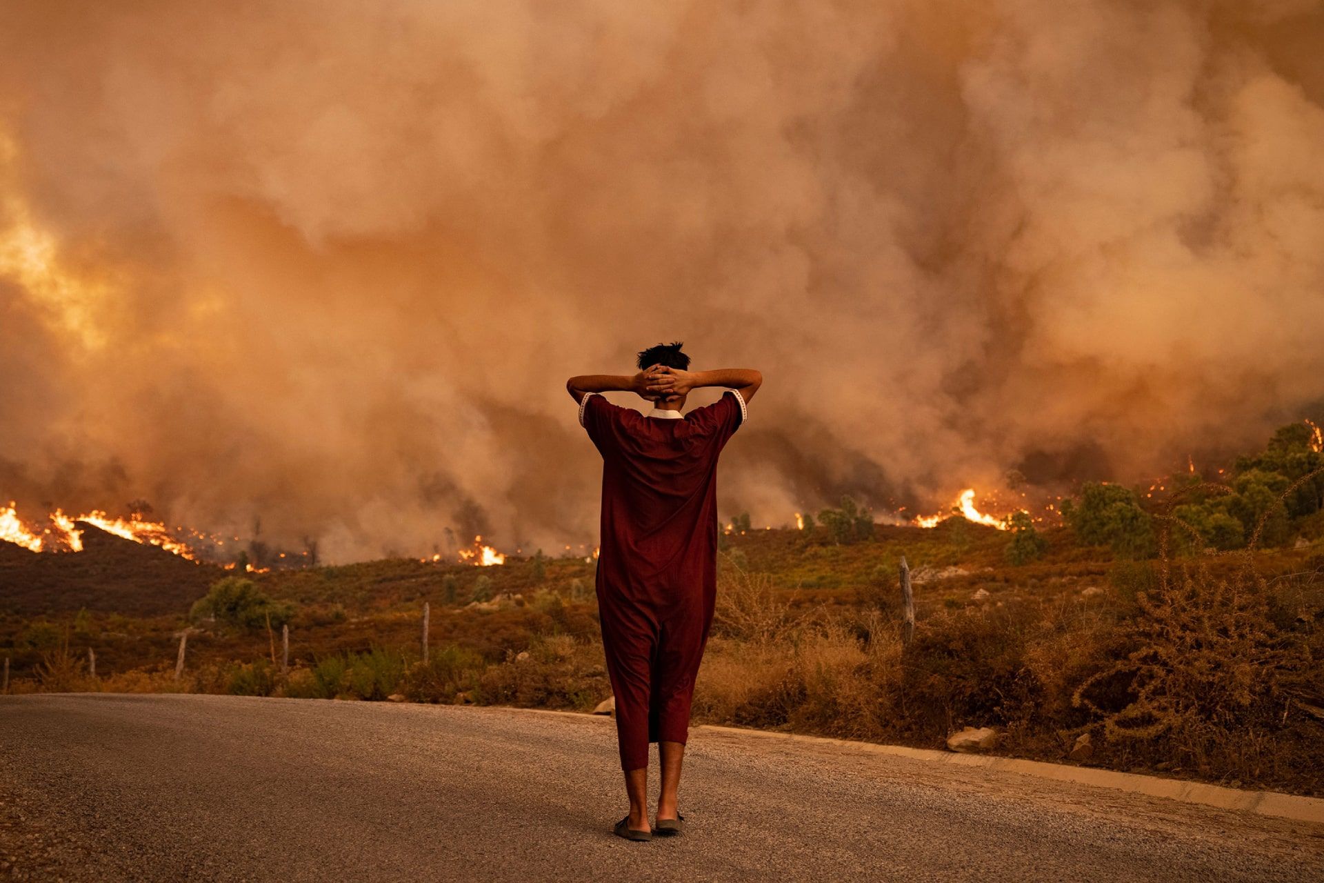 زنی به آتش‌سوزی‌های جنگلی در منطقه شفشاون در شمال مراکش نگاه می‌کند.