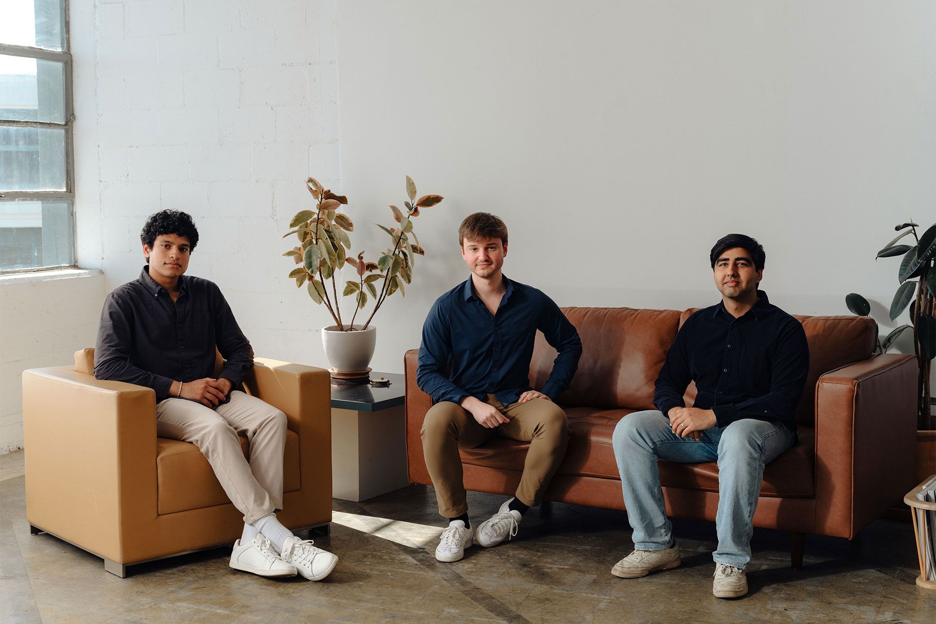 سه پسر جوان نشسته روی صندلی در حال نگاه به دوربین