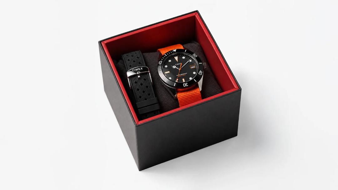 ساعت مچی تایمکس (Timex) با بندهای مشکی و نارنجی در جعبه مخصوص