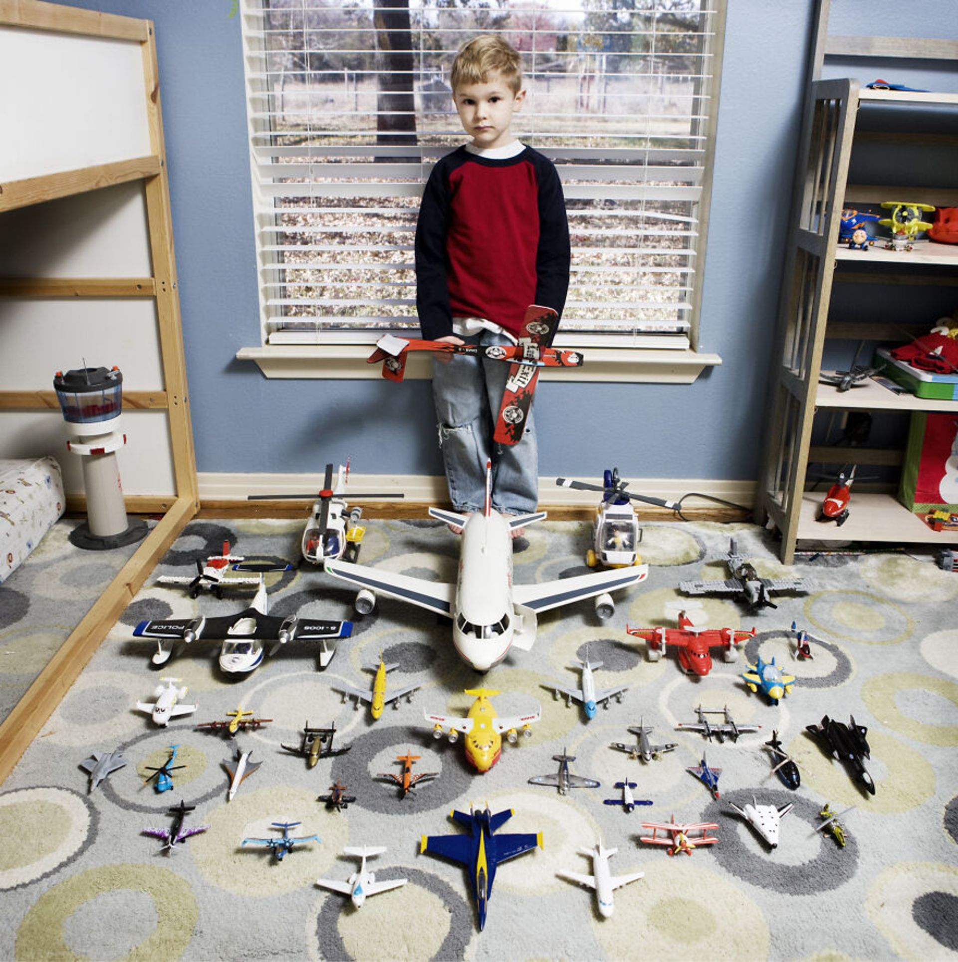 پسر بچه با هواپیماهای اسباب‌بازی