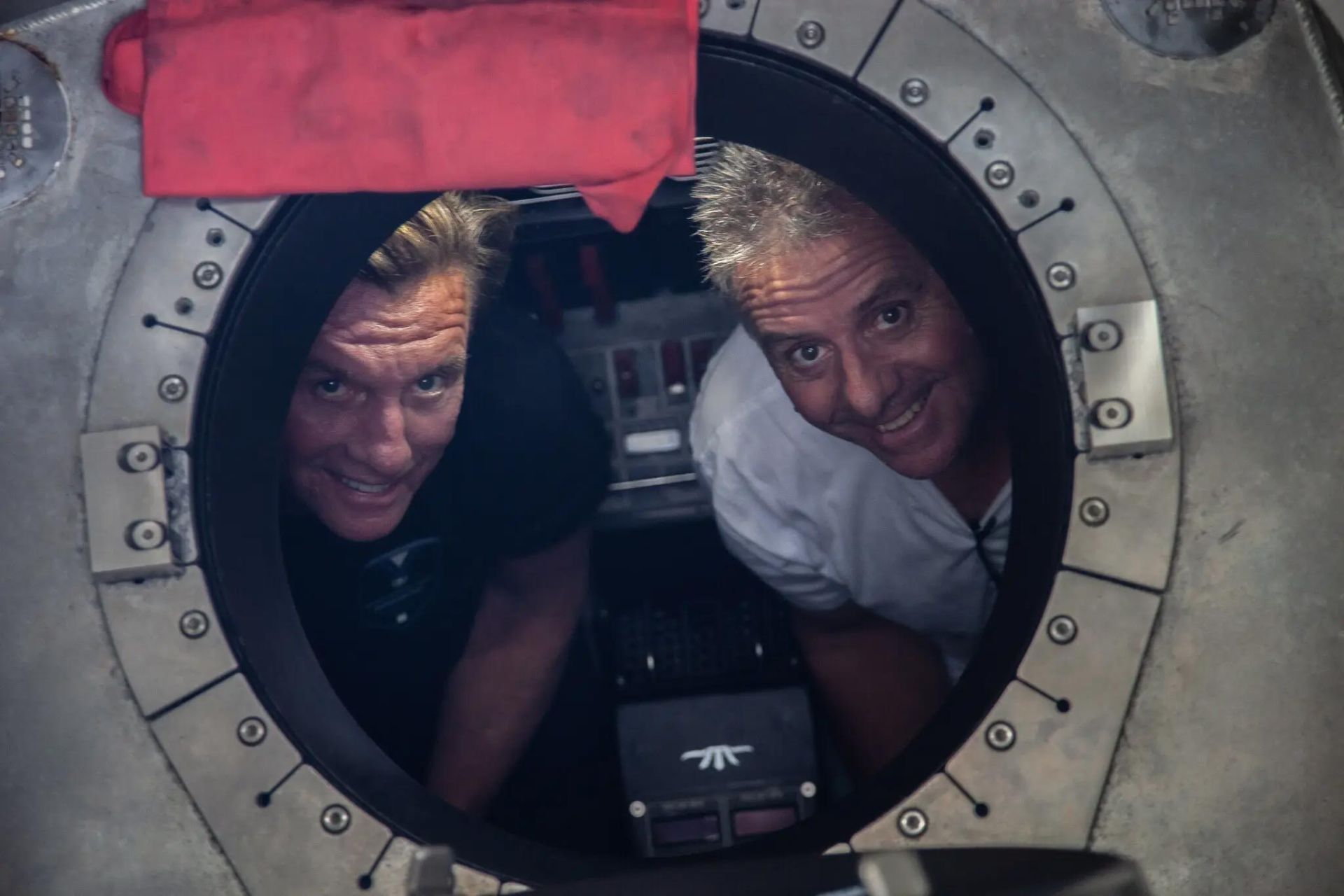 دو مرد از طریق پنجره دایره‌ای زیردریایی به بیرون نگاه می‌کنند