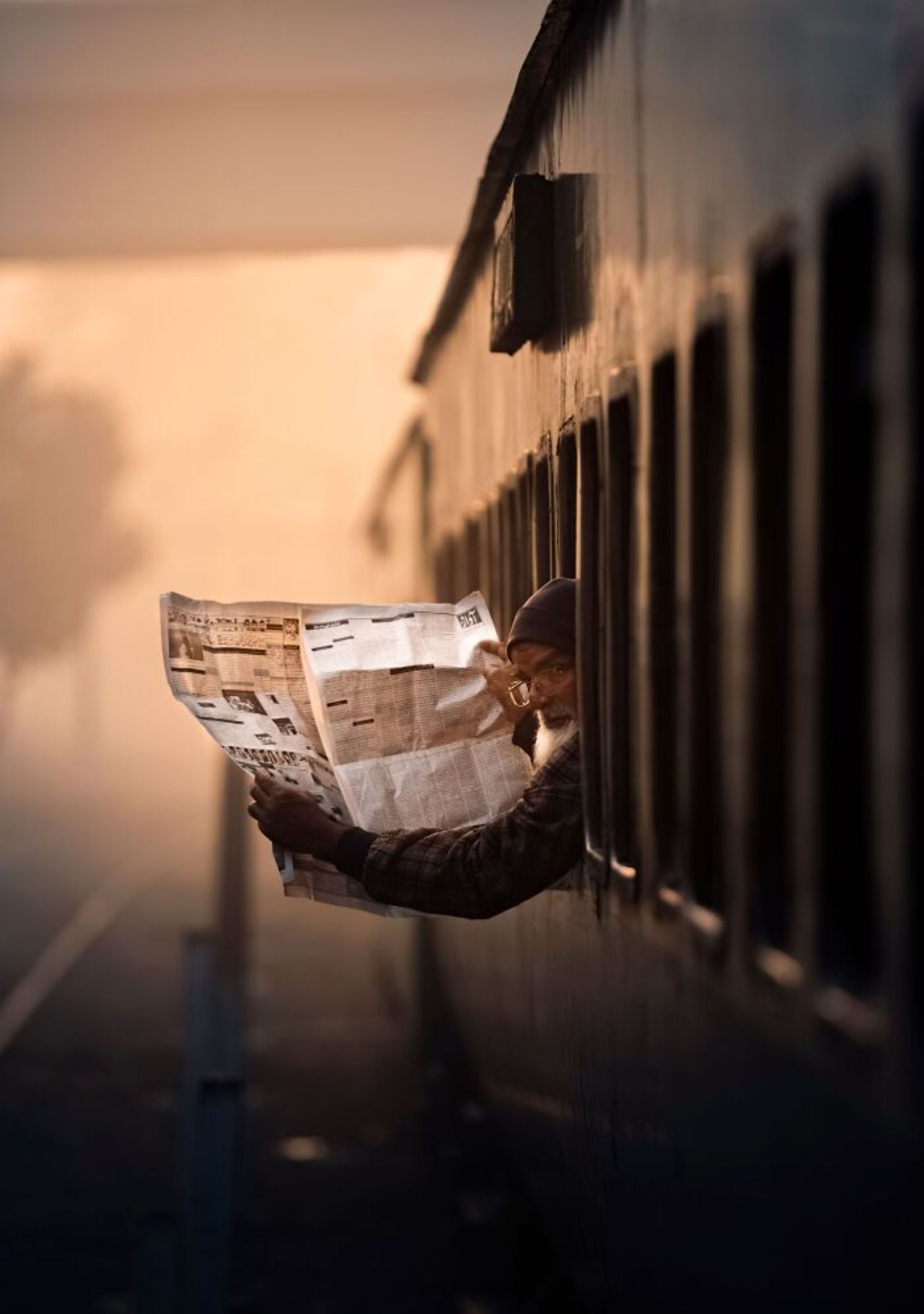 مرد روزنامه‌خوان در پنجره قطار