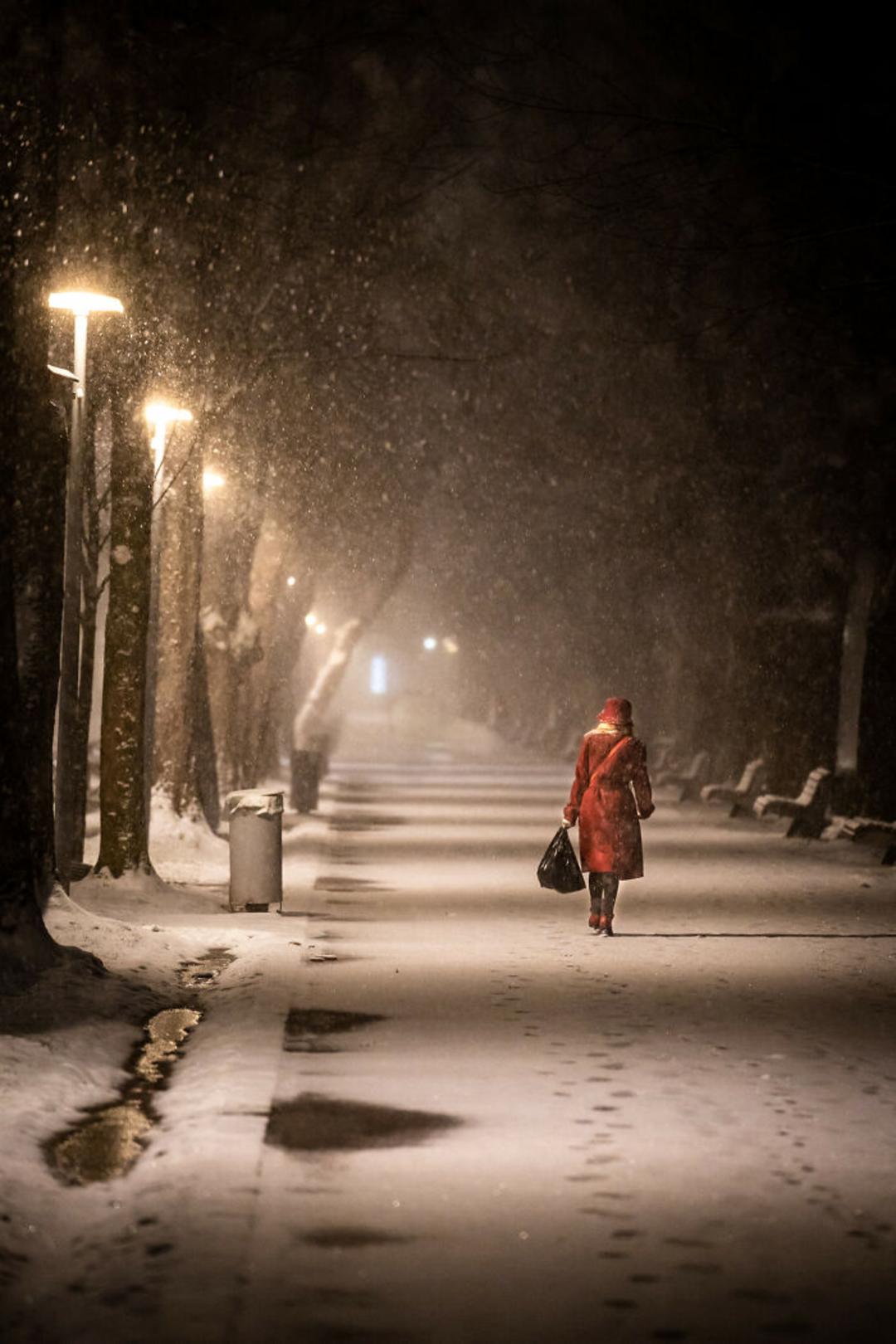 عابر زن با کت سرخ در خیابان برفی