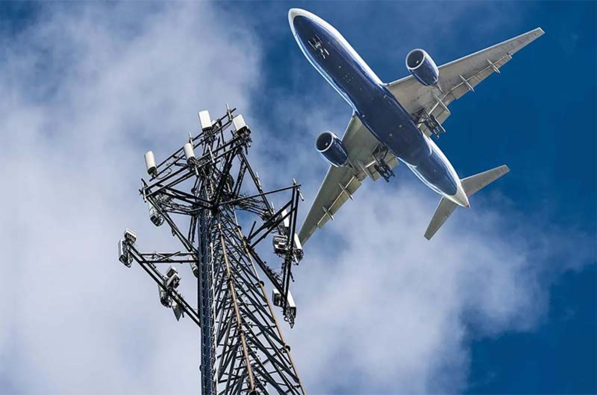 An airplane flies over a telecommunication tower.