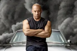 وین دیزل (Vin Diesel) با دست‌های گره‌خورده مقابل یک خودروی کلاسیک