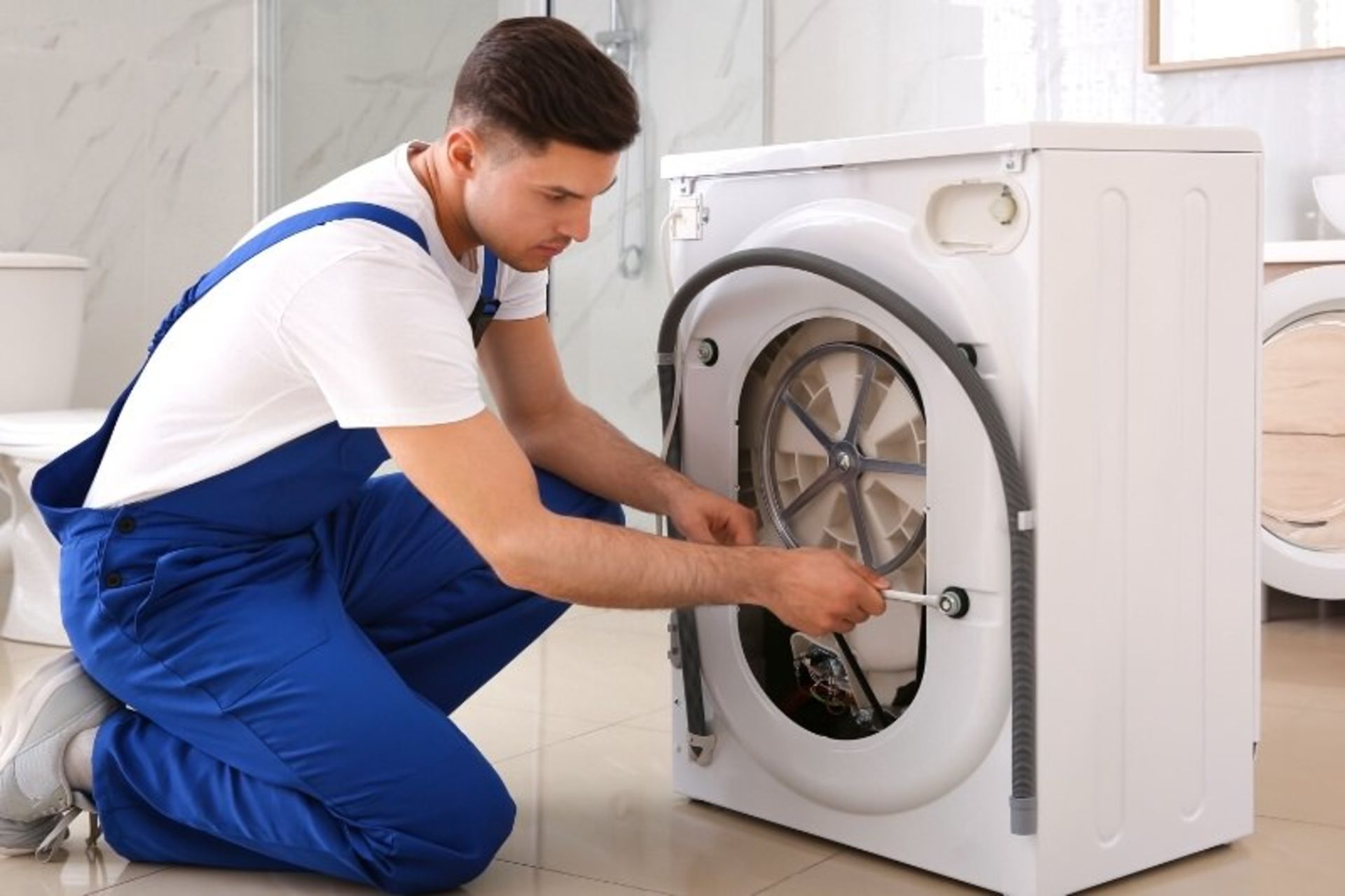 مردی در حال بازکردن پیچ‌های ترانزیت ماشین لباسشویی