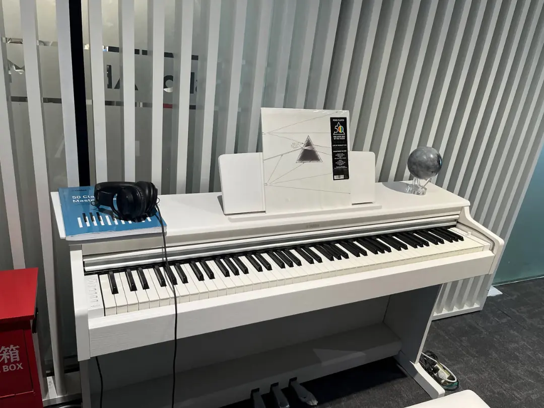 پیانو دیجیتال (Digital Piano) سفید رنگ روی میز در محیط اداری