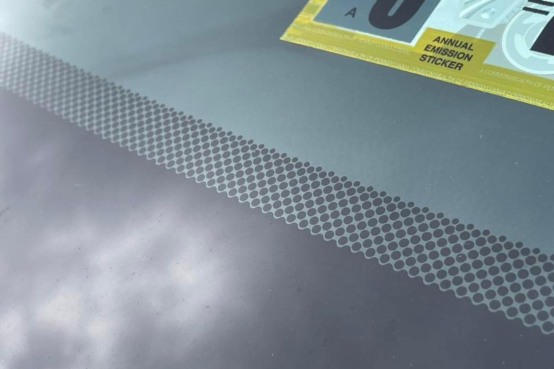 نوار و نقاط مشکی شیشه‌ی جلو یک خودرو از نمای نزدیک