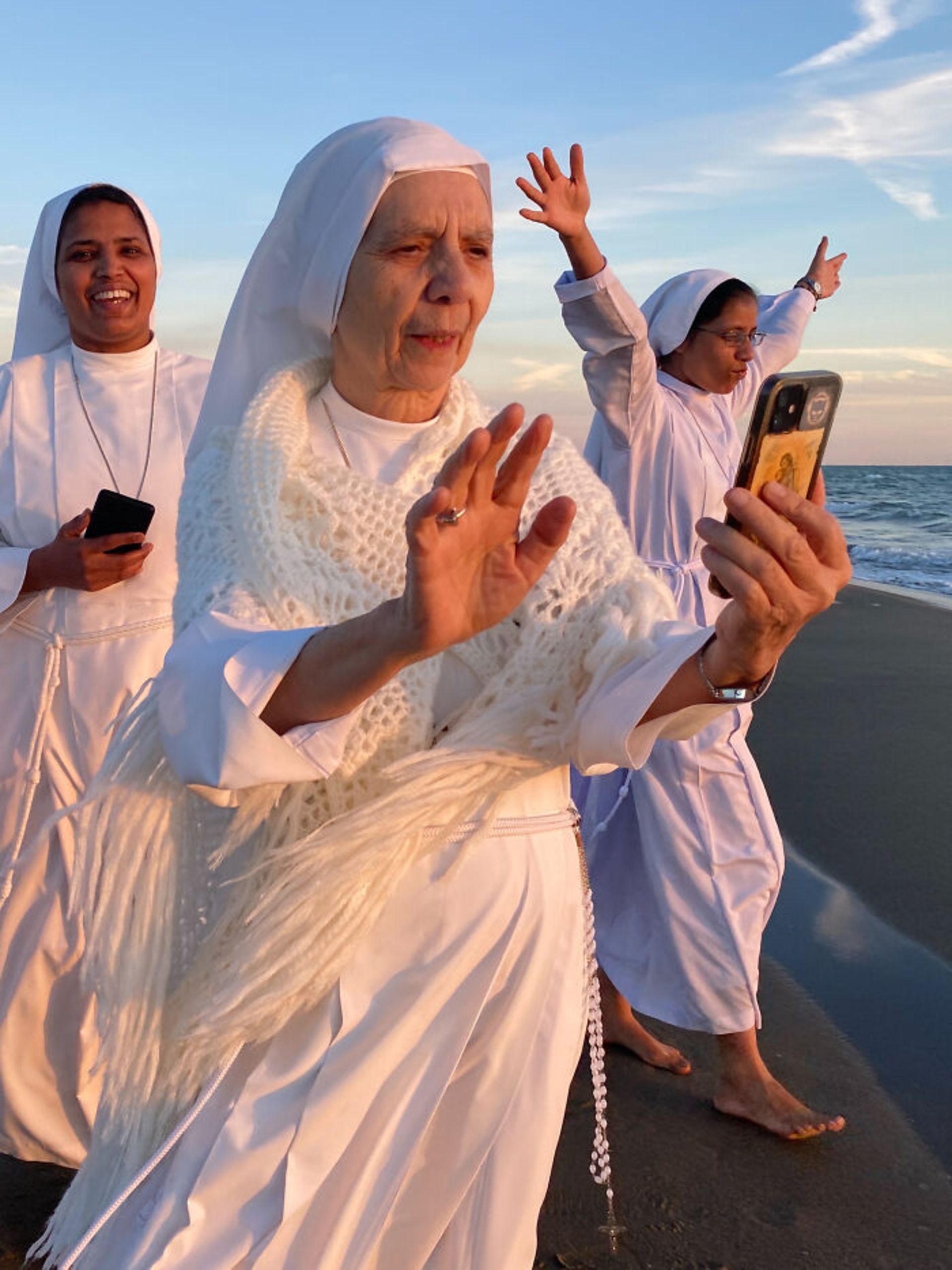راهبه‌ها در کنار ساحل با گوشی هوشمند