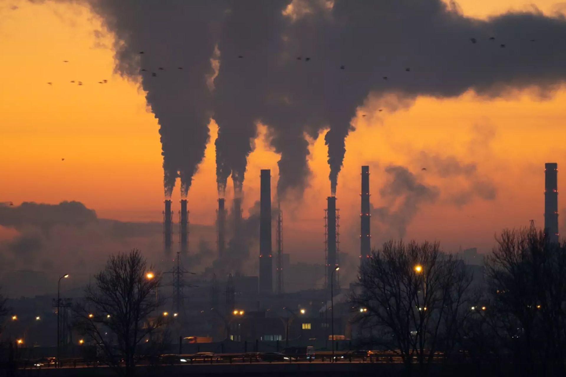 دود و آلودگی برخاسته از دودکش‌های نیروگاه زغال سنگ صنعتی در غروب نارنجی