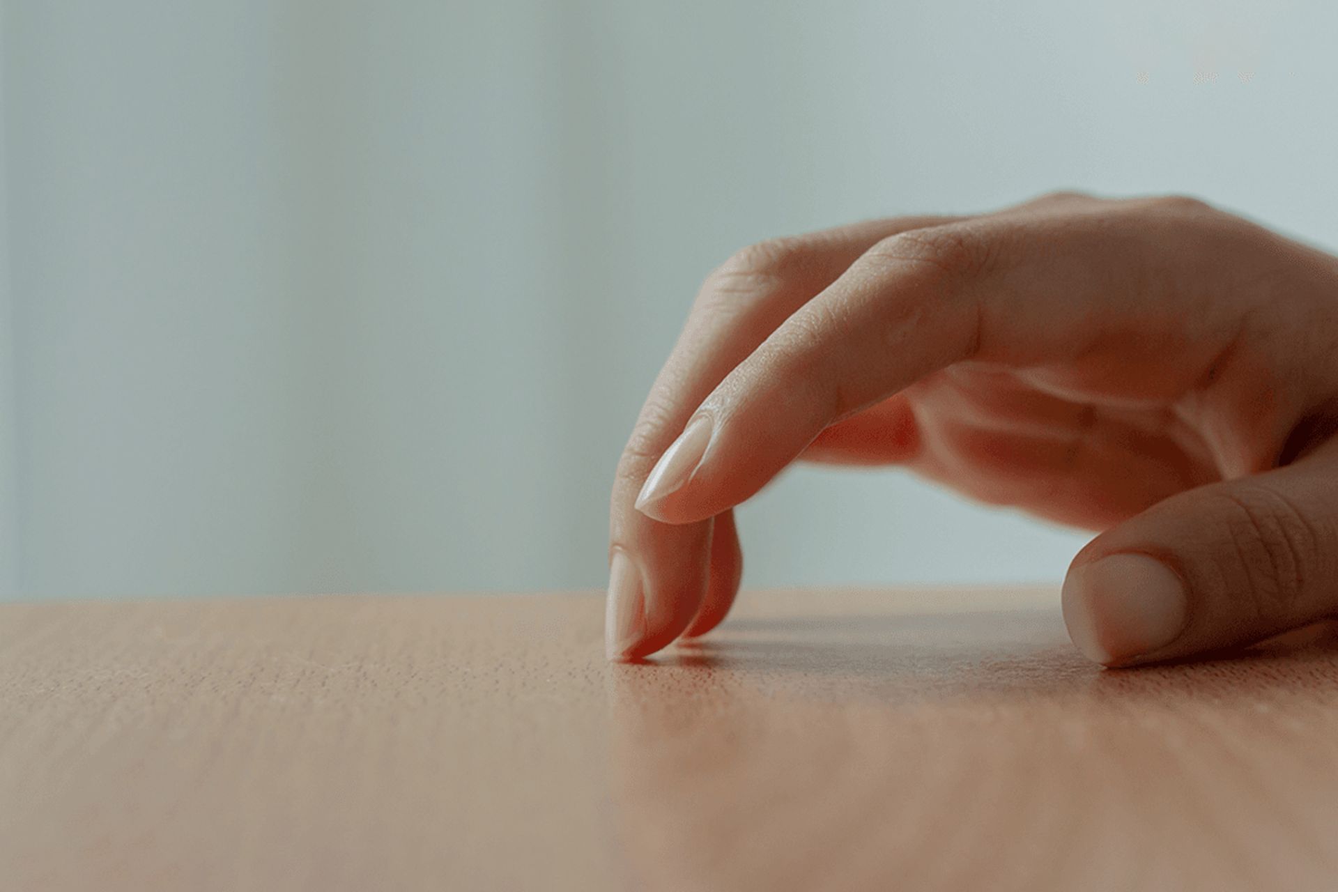 انگشتان دست خانمی روی میز ضربه می‌زند