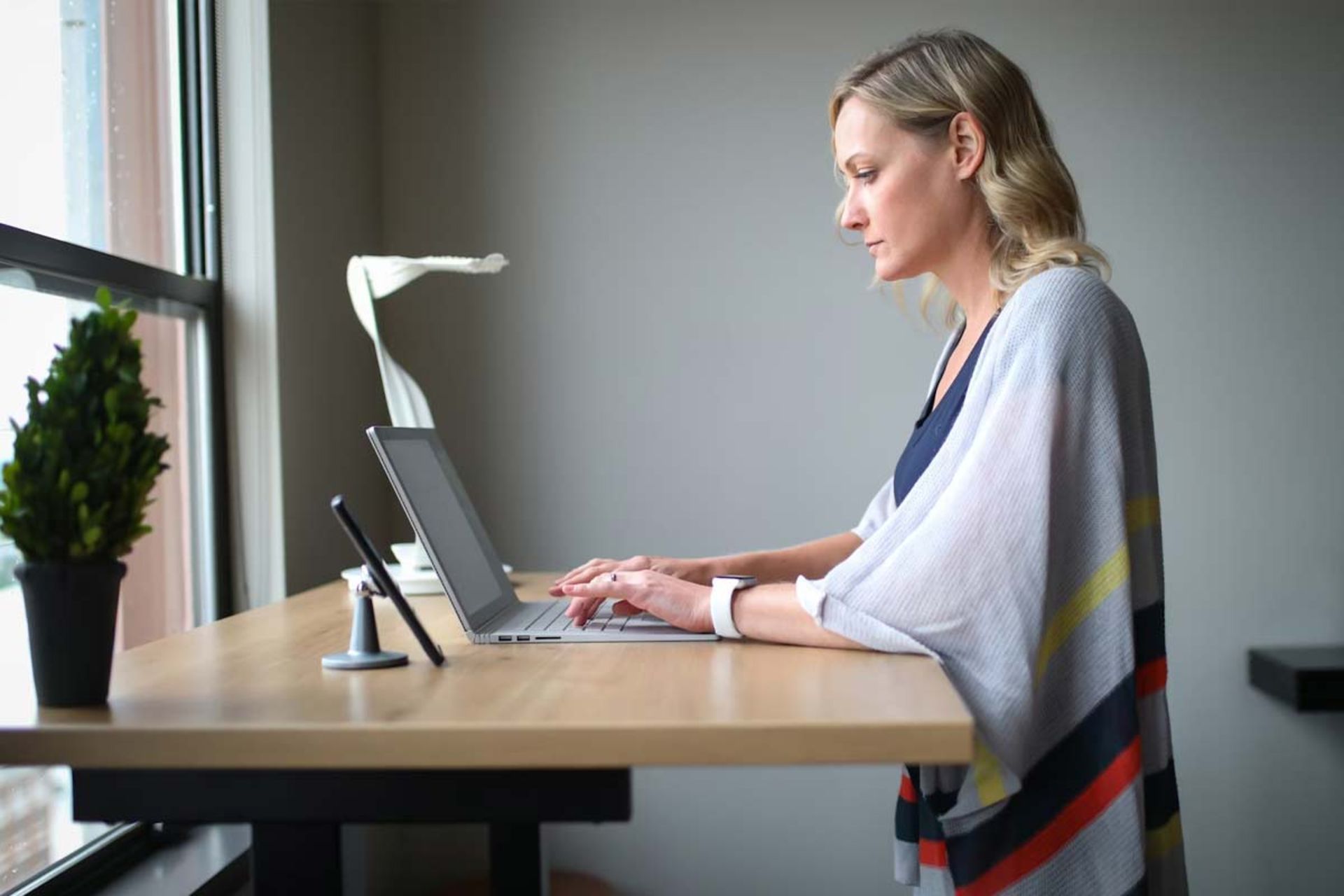 زنی با لباس سفید ایستاده در حال استفاده از لپ تاپ