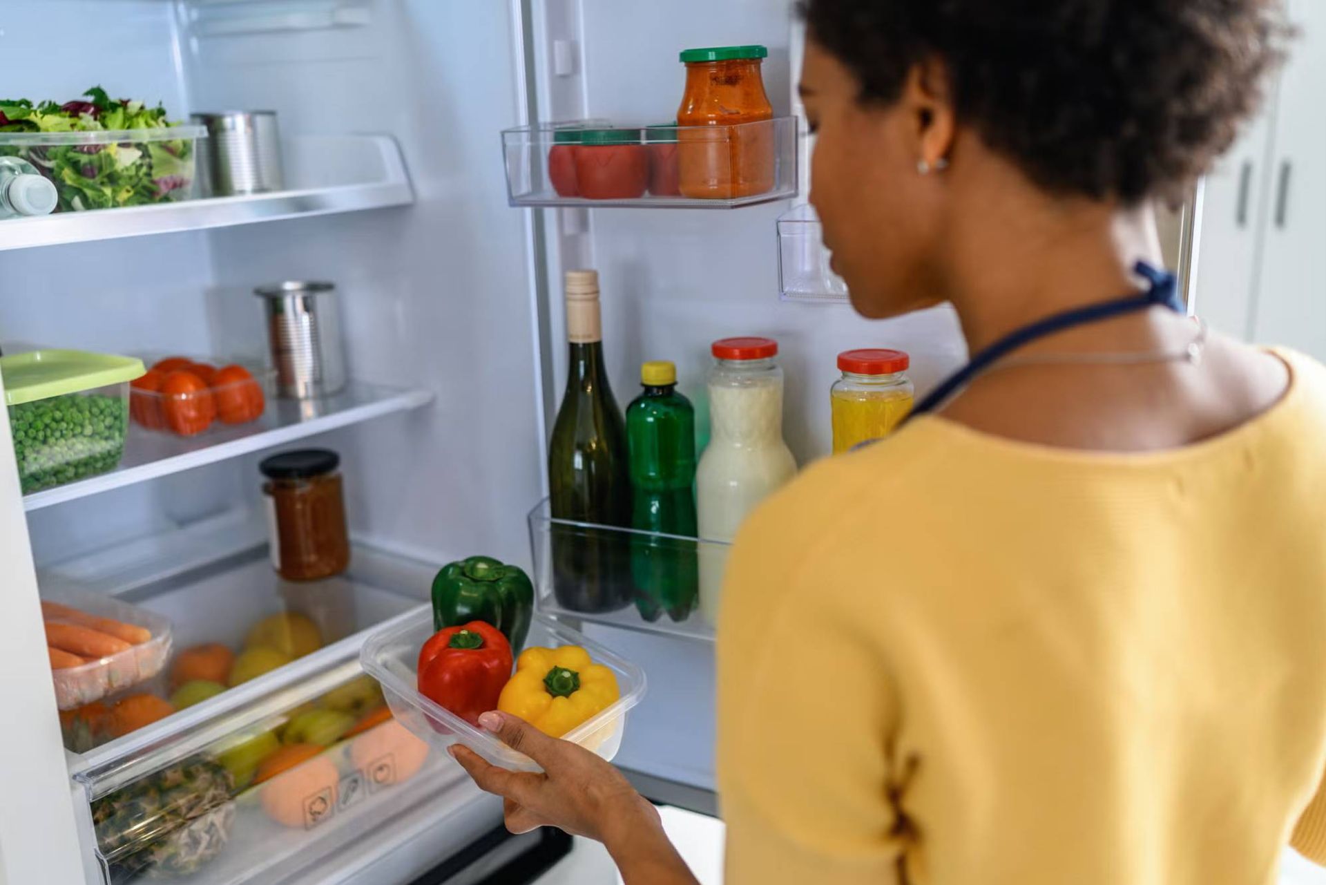 زنی درحال برداشتن غذا از یخچال