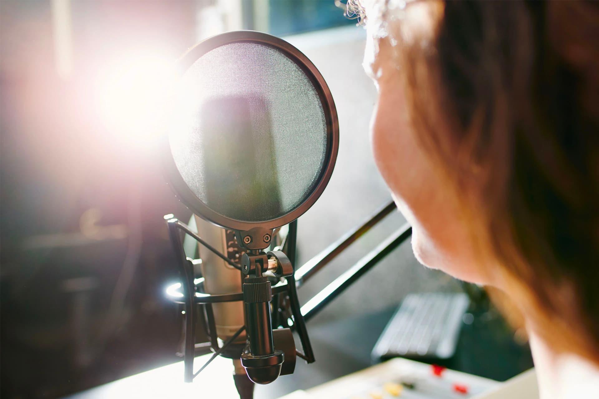 یک زن در حال ضبط صدا در جلوی میکروفون