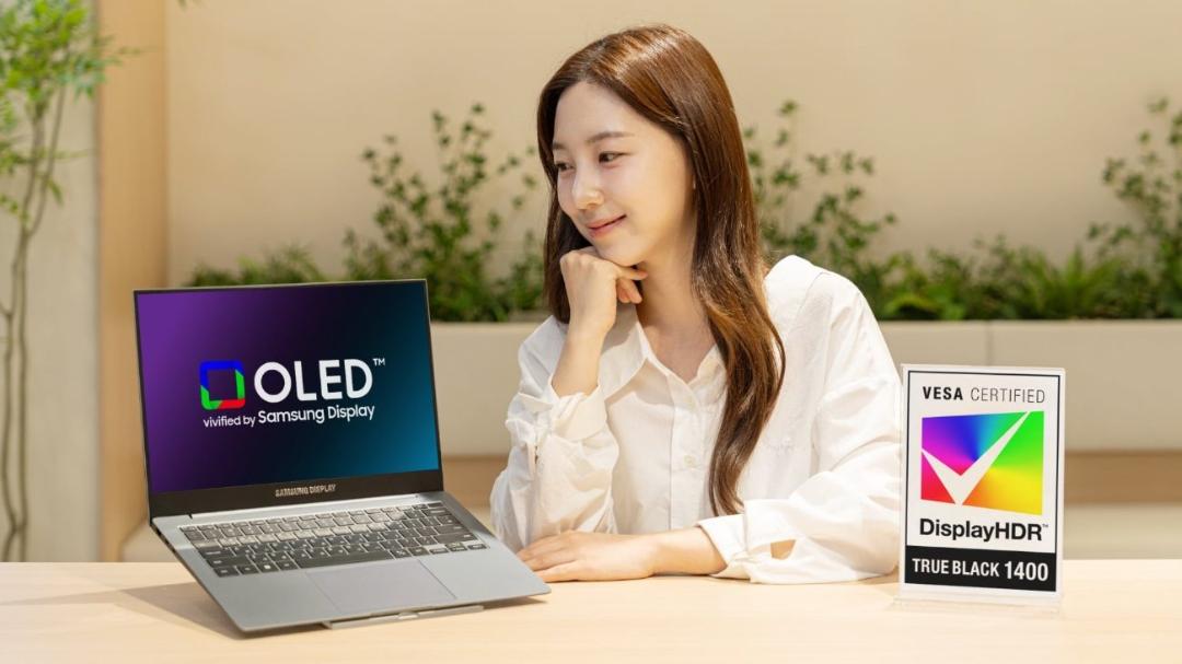 زنی در حال لبخند زدن و نگاه کردن به لپ‌تاپ سامسونگ با نمایشگر OLED و تاییدیه VESA DisplayHDR