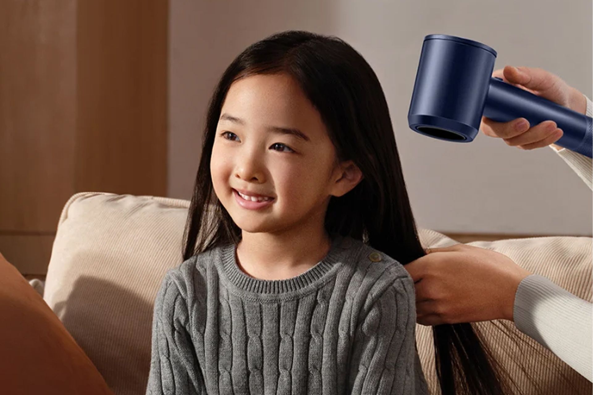 شخصی در حال سشوارکردن موهای یک دختربچه