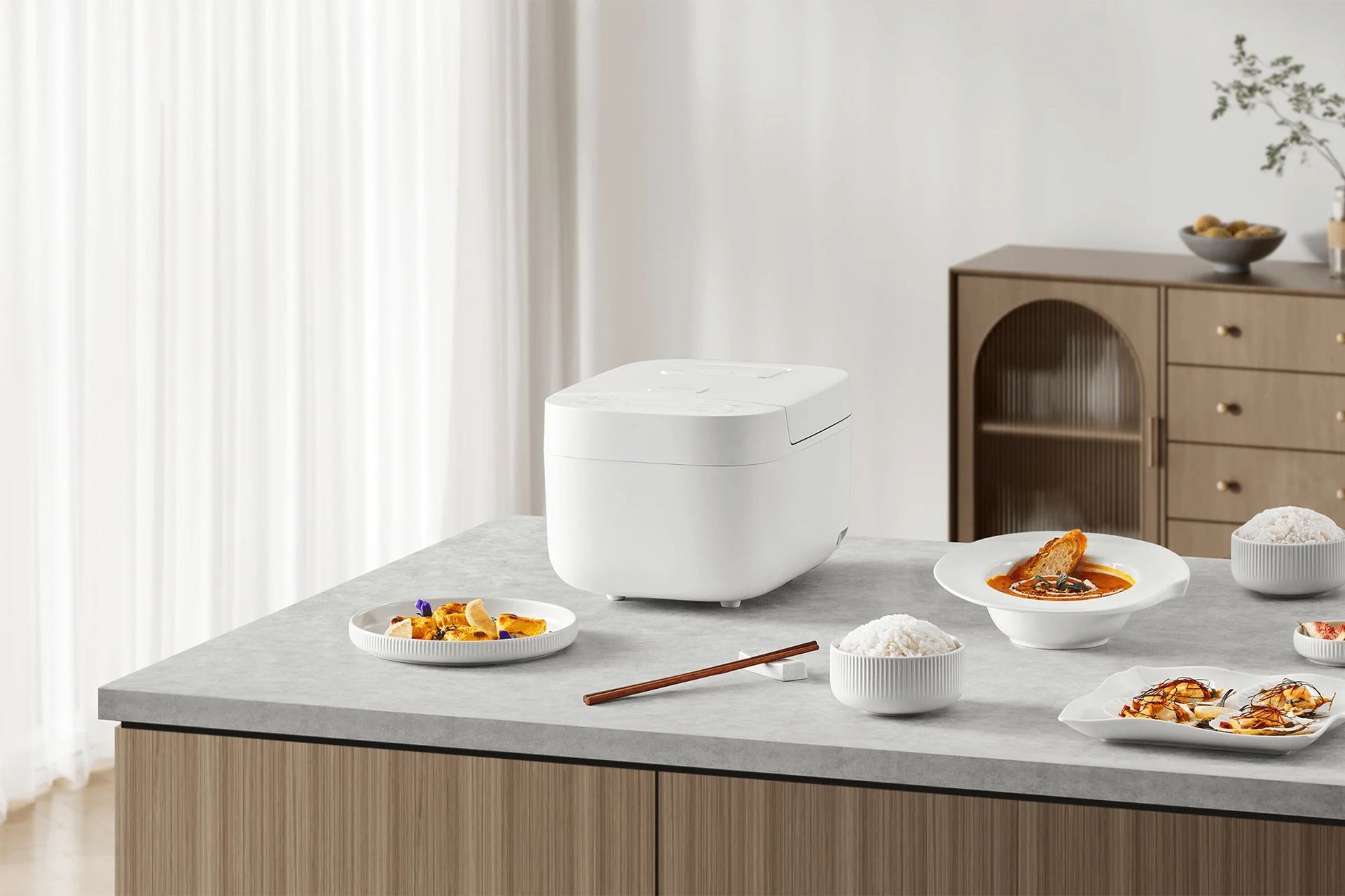 پلوپز هوشمند شیائومی روی میز آشپزخانه در کنار بشقاب‌های غذا