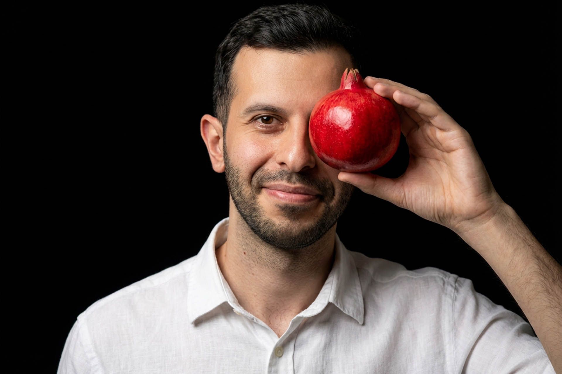 یک مرد که یک انار را در مقابل یک چشم خود گرفته - تصویر یلدایی