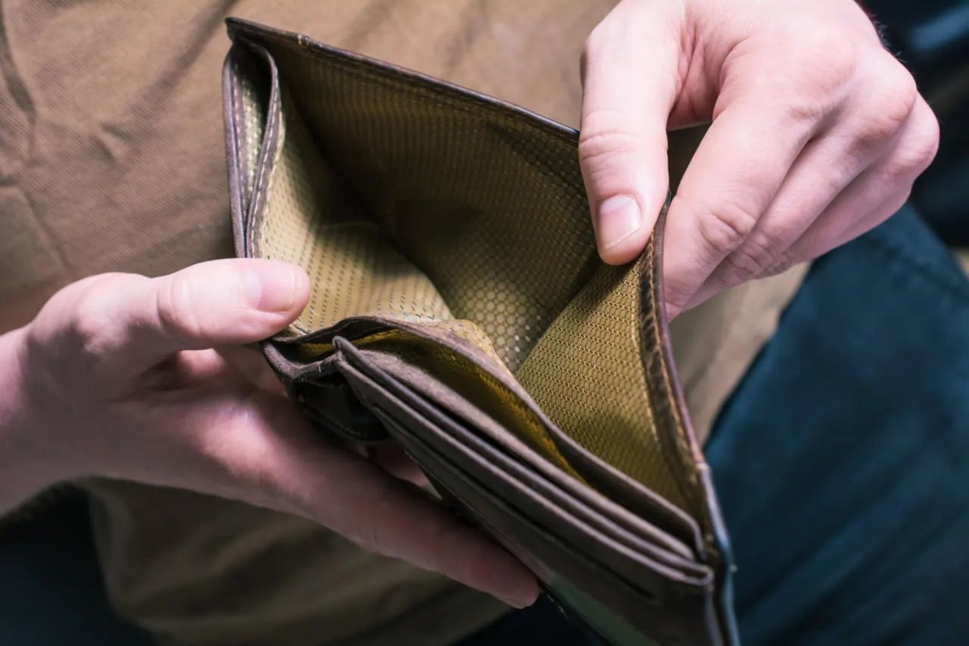 مرد جوان کیف پول خالی را در دست گرفته است