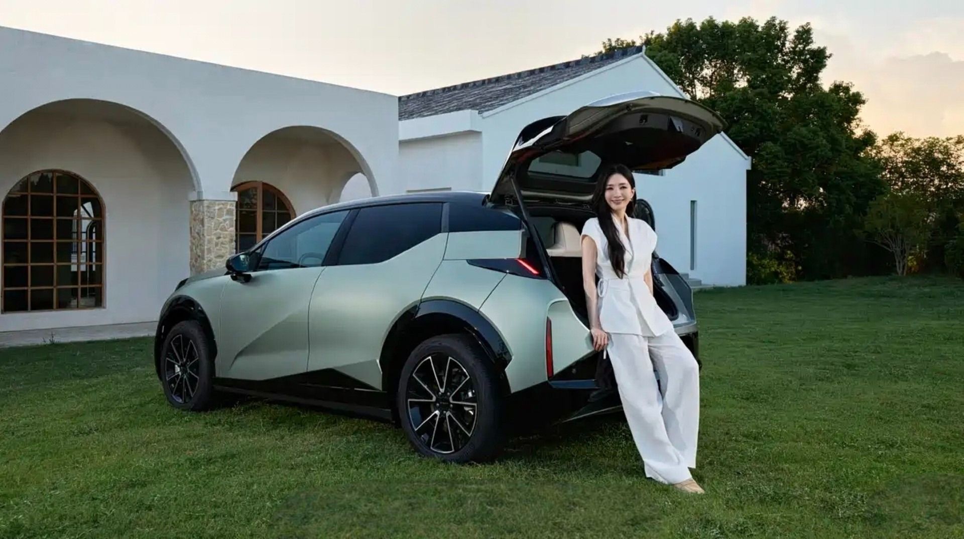 یک زن جوان کنار خودرو زیکر ایکس از نمای سه‌چهارم عقب